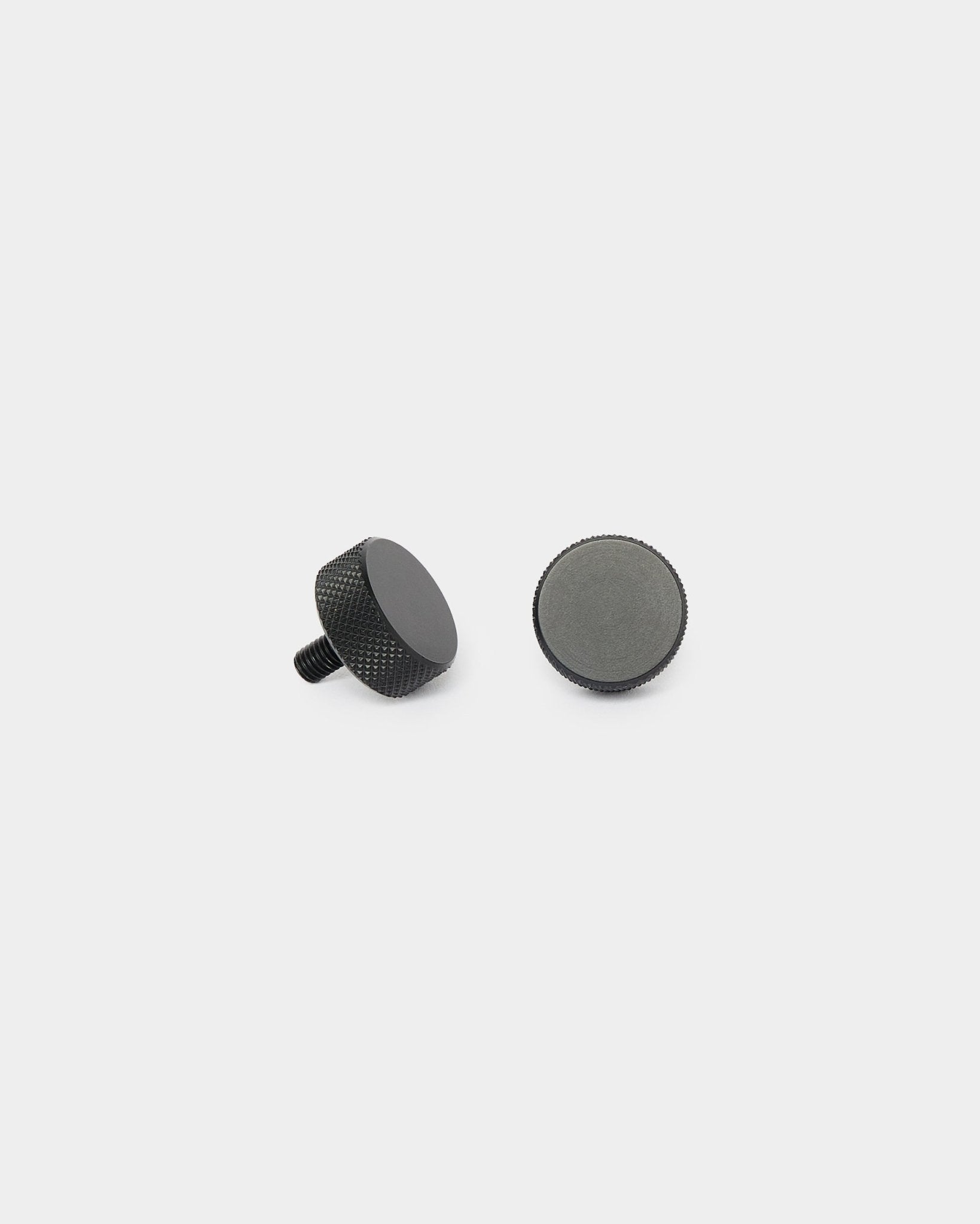 Dos tornillos Finger WoodUpp black (2 uds., M5x10 mm, 20x8.8), uno de pie y otro tumbado, sobre un fondo blanco liso para la instalación de Akupanel.